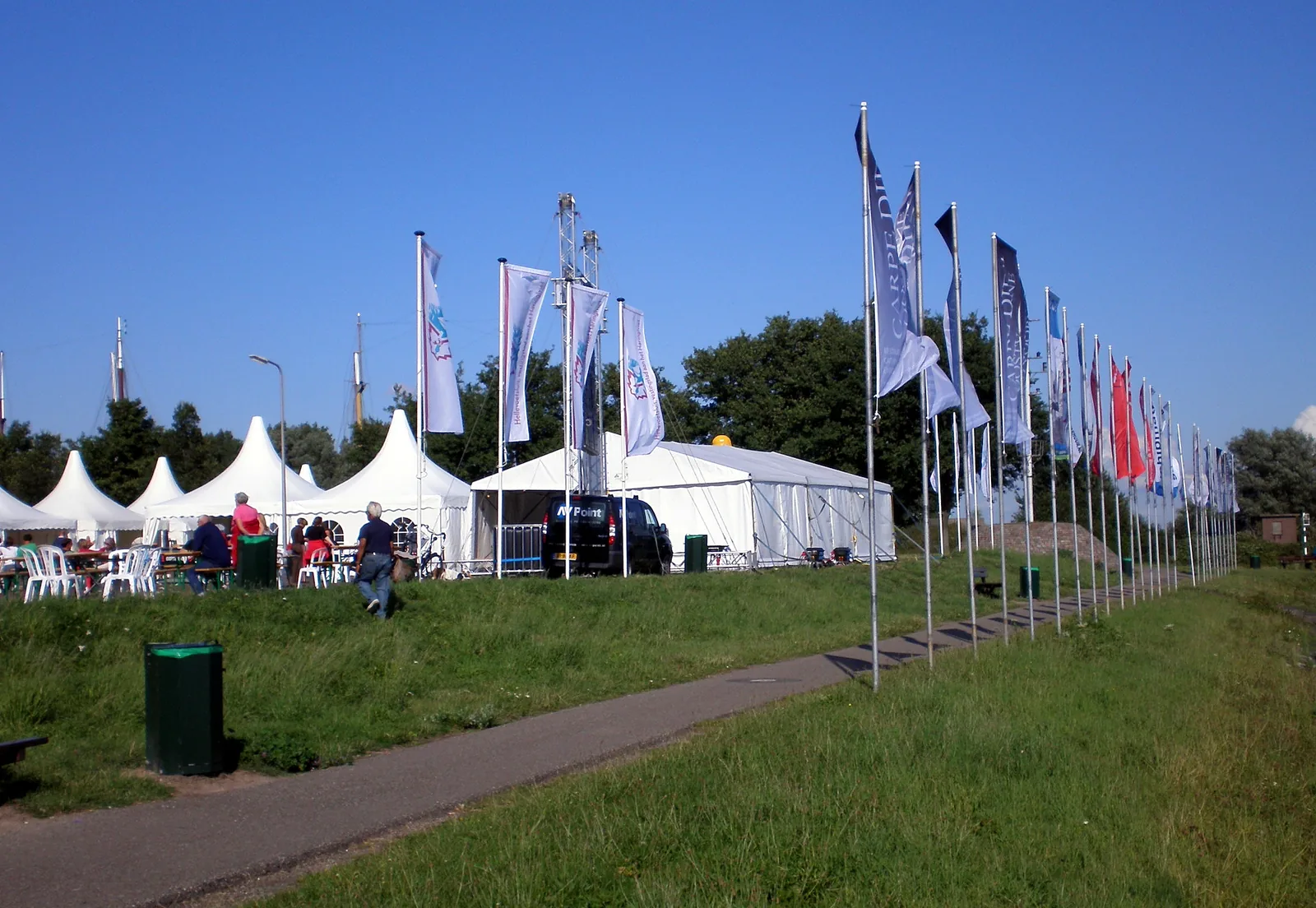 Vlaggenmasten in ballastbakken op een grasveld bij een evenement