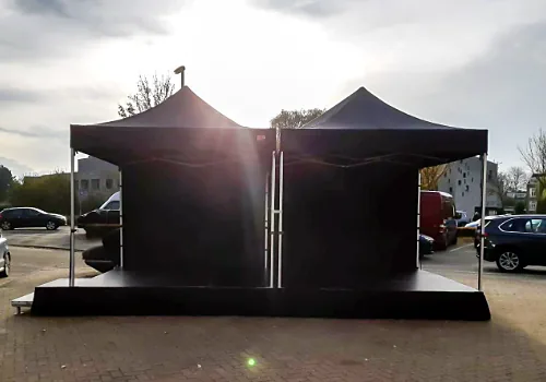 Twee zwarte partytenten aan elkaar gekoppeld, tegen de avondzon